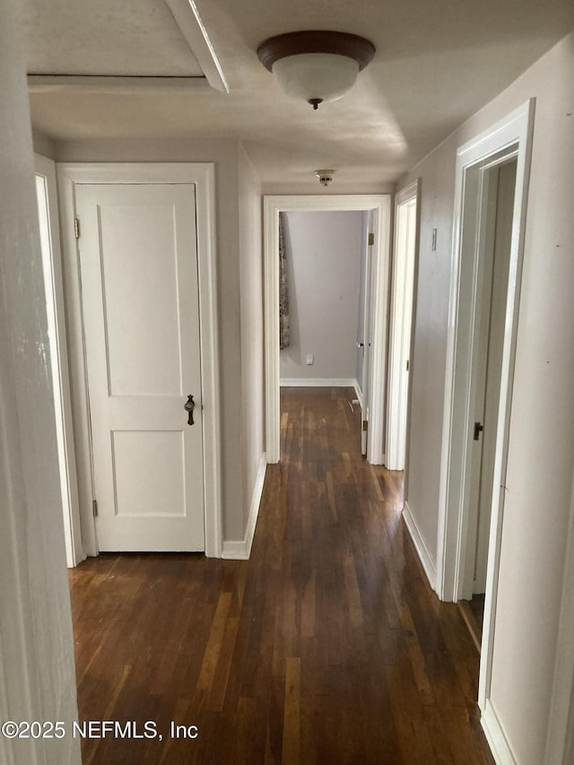 corridor with dark hardwood / wood-style flooring