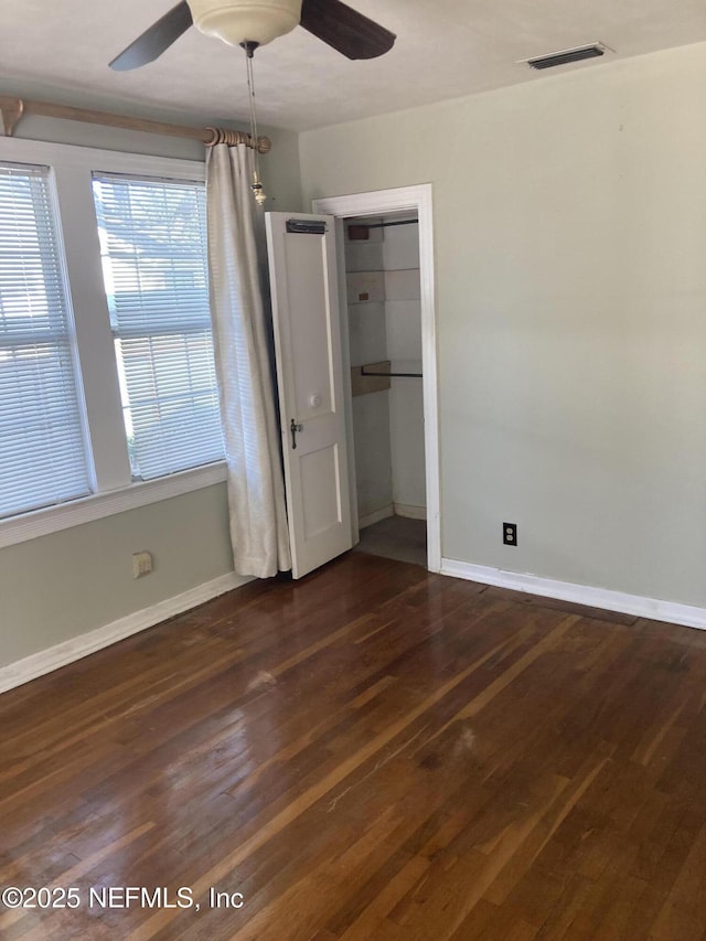 unfurnished bedroom featuring ceiling fan, dark hardwood / wood-style flooring, and a closet