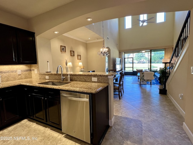 kitchen with stainless steel dishwasher, light stone countertops, kitchen peninsula, and sink