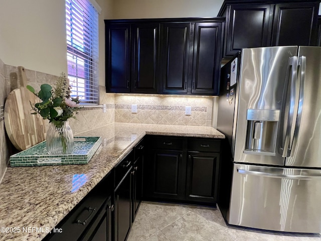 kitchen with backsplash, stainless steel fridge, light tile patterned floors, and light stone counters