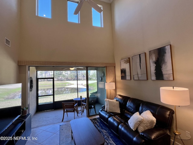 living room with a water view, ceiling fan, light tile patterned floors, and a high ceiling