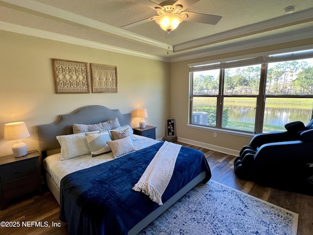 bedroom featuring ceiling fan, dark hardwood / wood-style floors, crown molding, a tray ceiling, and a water view