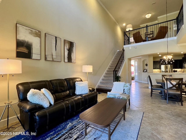 living room with tile patterned floors, crown molding, a chandelier, and a high ceiling