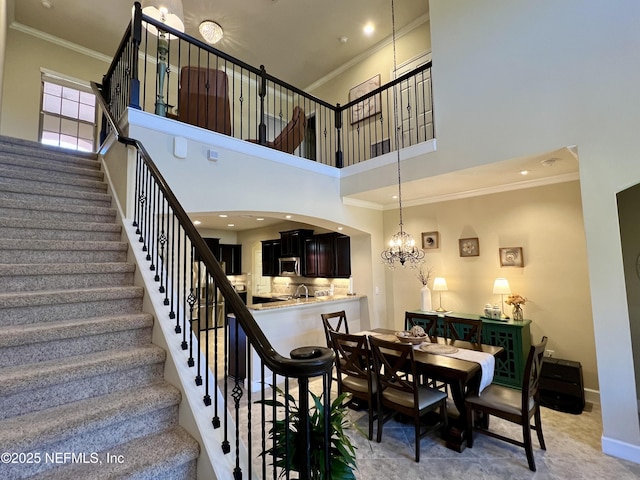 stairs featuring a chandelier, a towering ceiling, and crown molding