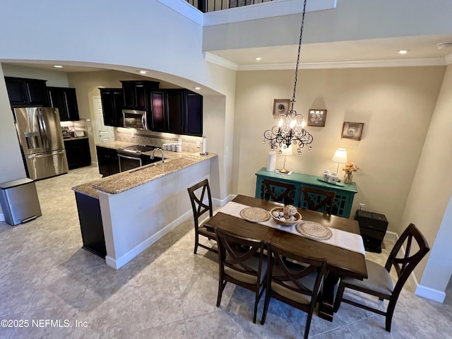 kitchen with kitchen peninsula, appliances with stainless steel finishes, decorative backsplash, light tile patterned floors, and a notable chandelier