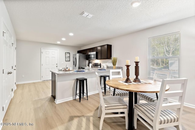 dining space featuring light wood-type flooring and a textured ceiling