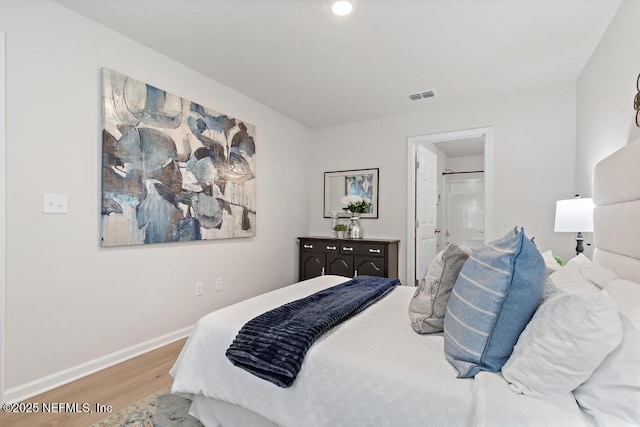 bedroom with connected bathroom and wood-type flooring