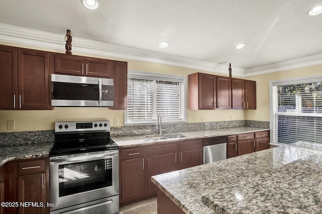 kitchen with appliances with stainless steel finishes, light stone counters, crown molding, and sink