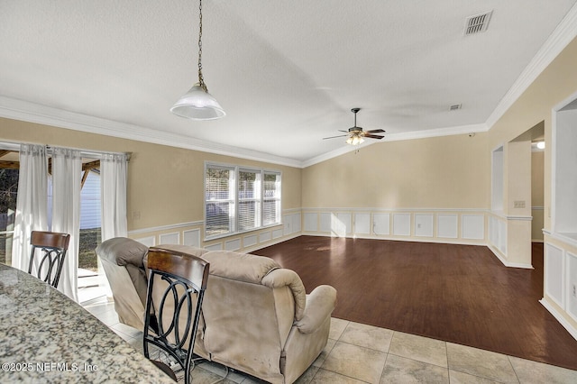 tiled living room featuring a textured ceiling, lofted ceiling, ceiling fan, and ornamental molding