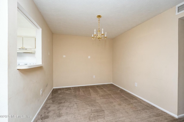 carpeted empty room featuring a textured ceiling and an inviting chandelier