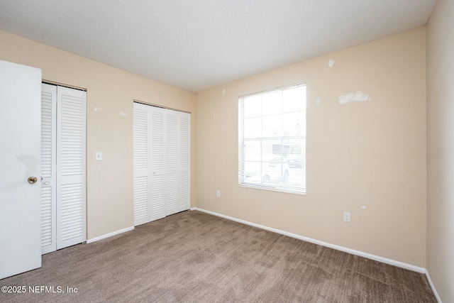 unfurnished bedroom featuring carpet flooring and multiple closets