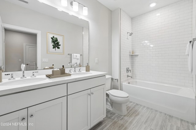 full bathroom featuring tiled shower / bath combo, toilet, wood-type flooring, and vanity