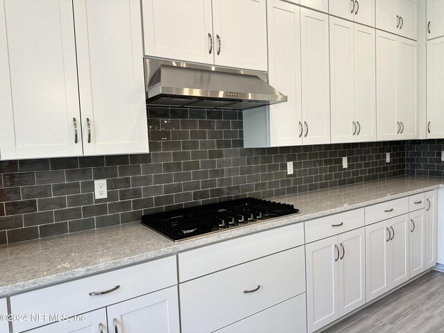 kitchen with white cabinets, backsplash, ventilation hood, and black gas cooktop