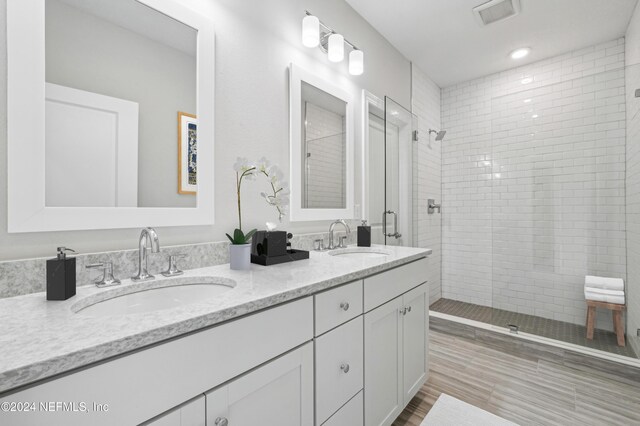 bathroom featuring a shower with door and vanity