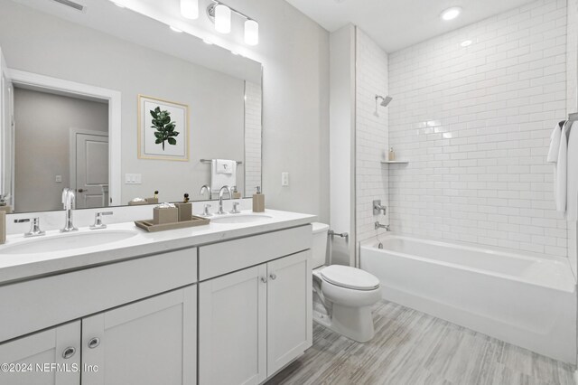 full bathroom with tiled shower / bath combo, toilet, wood-type flooring, and vanity