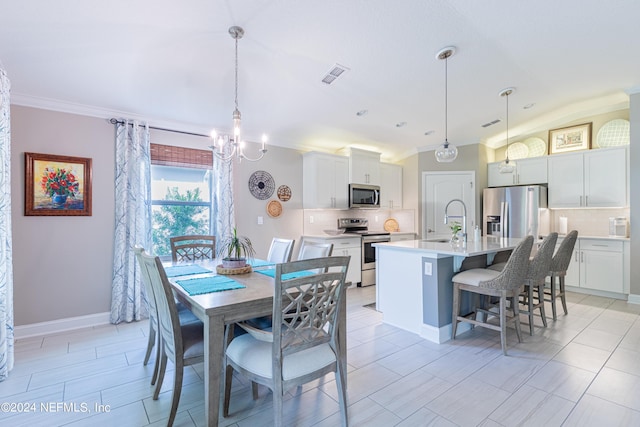 dining area with sink, crown molding, a chandelier, lofted ceiling, and light tile patterned flooring