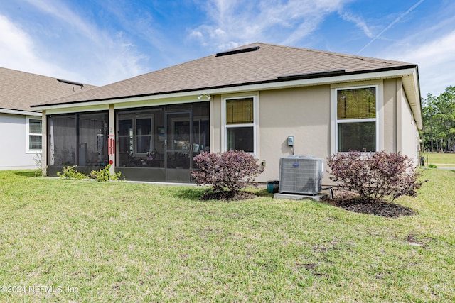 back of property with a sunroom, cooling unit, and a lawn