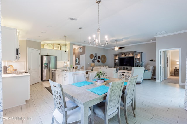 dining space featuring ceiling fan with notable chandelier, crown molding, and sink