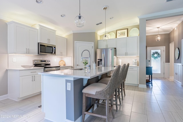 kitchen featuring sink, stainless steel appliances, vaulted ceiling, a kitchen island with sink, and a breakfast bar