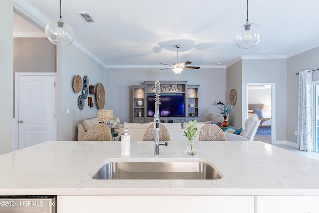 kitchen with light stone counters, an island with sink, and decorative light fixtures