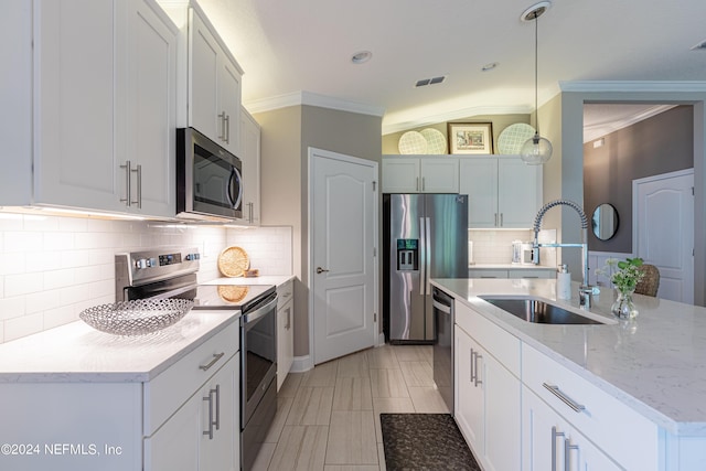 kitchen with tasteful backsplash, stainless steel appliances, sink, pendant lighting, and white cabinets