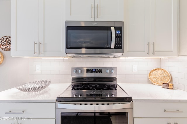 kitchen with decorative backsplash, white cabinets, stainless steel appliances, and light stone counters