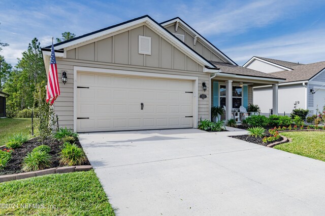 view of front of property with a front lawn, covered porch, and a garage