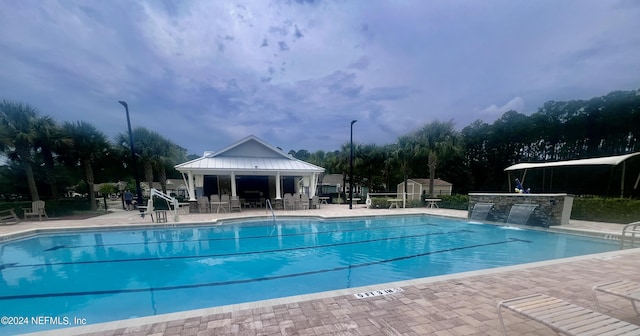 view of pool featuring pool water feature, a patio, and an outdoor structure