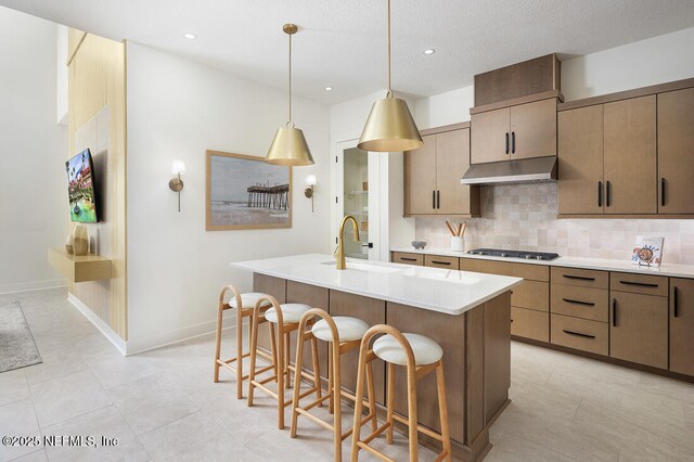86 Delwood Way Unit 269, Saint Augustine, FL 32092 - kitchen featuring stainless steel gas cooktop, hanging light fixtures, a kitchen breakfast bar, backsplash, and an island with sink