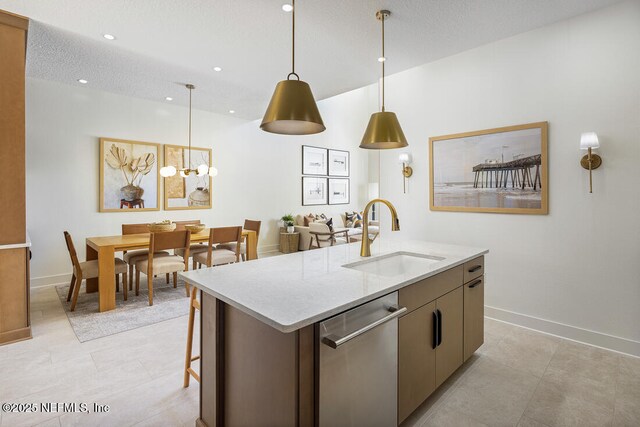 86 Delwood Way Unit 269, Saint Augustine, FL 32092 - kitchen with a textured ceiling, a kitchen island with sink, stainless steel dishwasher, sink, and decorative light fixtures