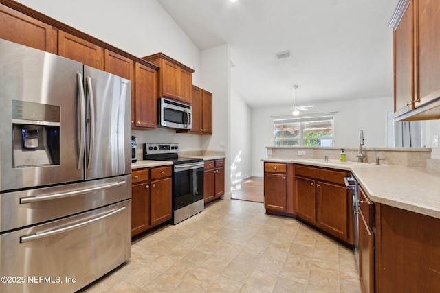 kitchen with appliances with stainless steel finishes, vaulted ceiling, ceiling fan, and sink