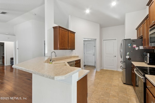 kitchen with kitchen peninsula, a towering ceiling, stainless steel appliances, sink, and a breakfast bar area