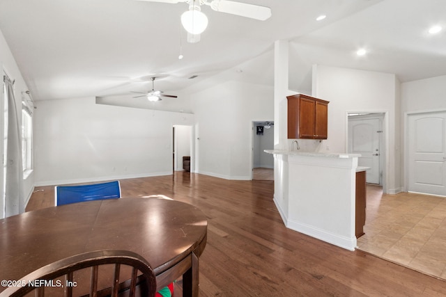 interior space featuring hardwood / wood-style floors, ceiling fan, lofted ceiling, and kitchen peninsula