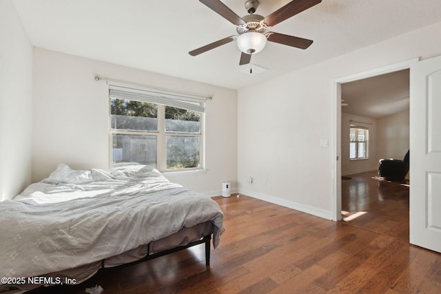 bedroom with multiple windows, ceiling fan, and dark wood-type flooring