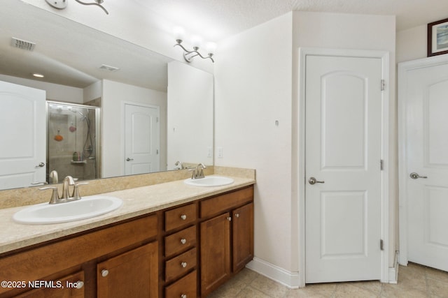 bathroom with a textured ceiling, vanity, tile patterned floors, and a shower with door