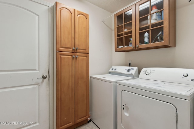 laundry room with washing machine and clothes dryer and cabinets