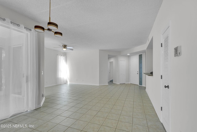 tiled empty room featuring ceiling fan and a textured ceiling