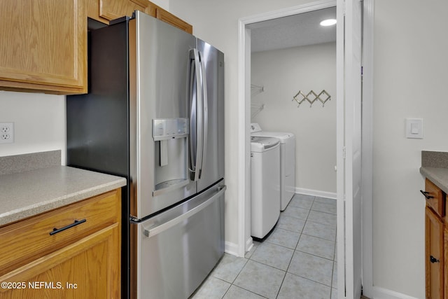 kitchen with light brown cabinetry, washer and clothes dryer, light tile patterned floors, and stainless steel refrigerator with ice dispenser