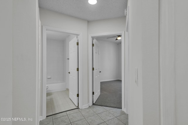 corridor with light tile patterned floors and a textured ceiling