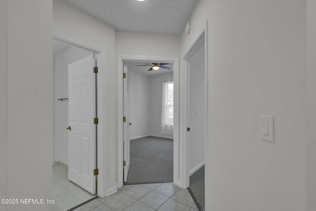 hallway with light tile patterned floors and a textured ceiling