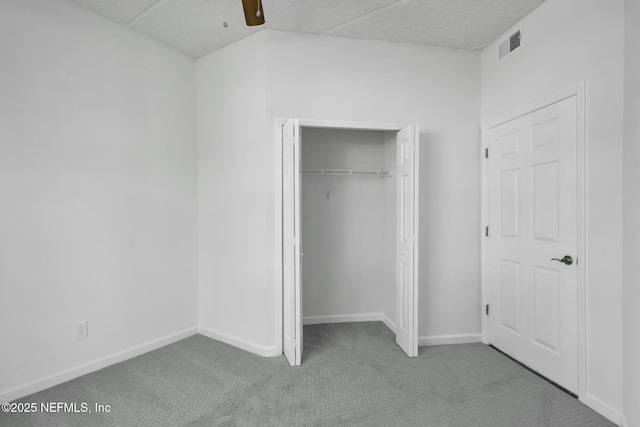 unfurnished bedroom featuring ceiling fan, light colored carpet, and a closet