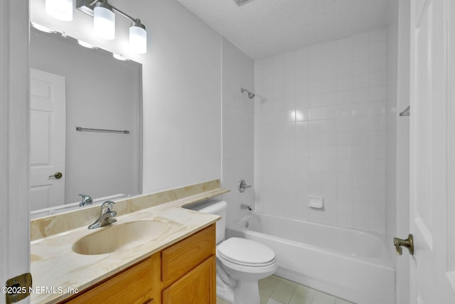 full bathroom featuring vanity, tile patterned floors, tiled shower / bath, toilet, and a textured ceiling