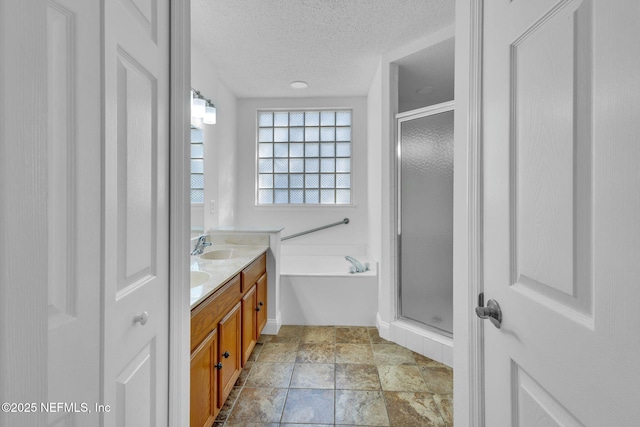 bathroom with a textured ceiling, vanity, and shower with separate bathtub