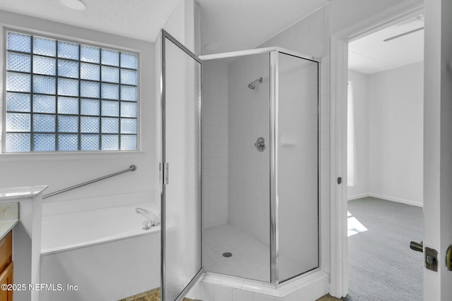 bathroom featuring a textured ceiling, vanity, and shower with separate bathtub