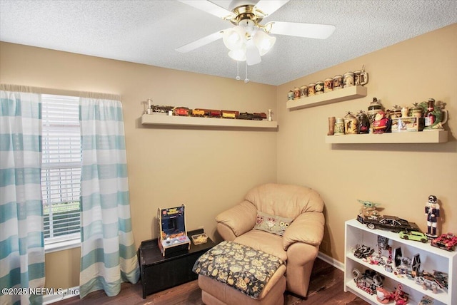 sitting room featuring a textured ceiling, dark hardwood / wood-style floors, a wealth of natural light, and ceiling fan