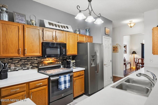 kitchen featuring sink, backsplash, pendant lighting, a textured ceiling, and appliances with stainless steel finishes