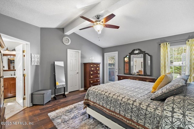 bedroom with connected bathroom, ceiling fan, dark wood-type flooring, vaulted ceiling with beams, and a textured ceiling