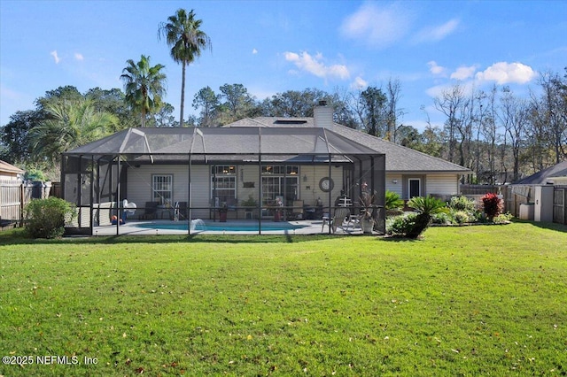 back of property with a fenced in pool, glass enclosure, a patio area, and a lawn