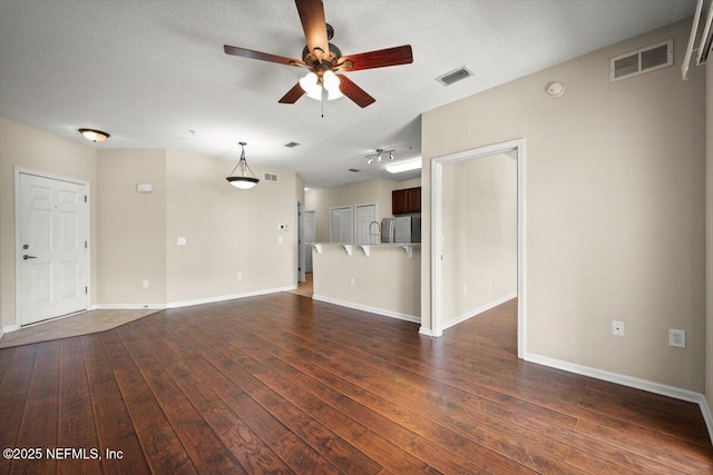 unfurnished living room featuring a textured ceiling, ceiling fan, and dark hardwood / wood-style floors