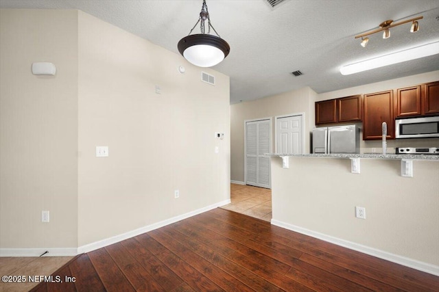 kitchen featuring appliances with stainless steel finishes, a breakfast bar, light hardwood / wood-style floors, and light stone countertops